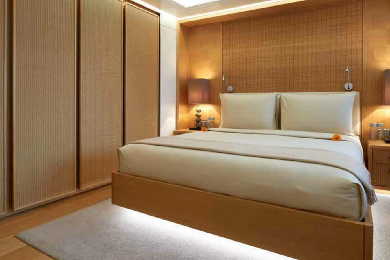 The stateroom features a luxurious bed with elegant lighting and warm wooden accents. aboard DYTAN Yacht for Sale