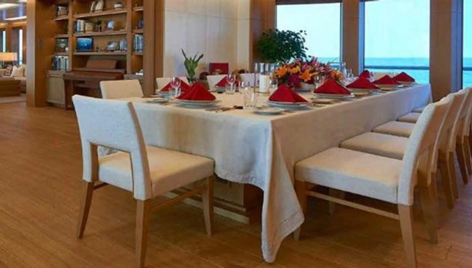The yacht's dining area features a large table set for a formal meal, surrounded by comfortable chairs and accented with floral arrangements. aboard DYTAN Yacht for Sale