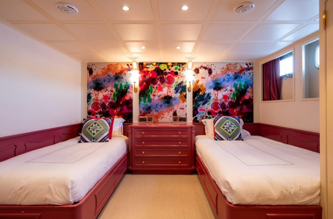 The guest stateroom features twin beds with vibrant, colorful artwork on the walls. aboard STELLA FIERA II Yacht for Sale