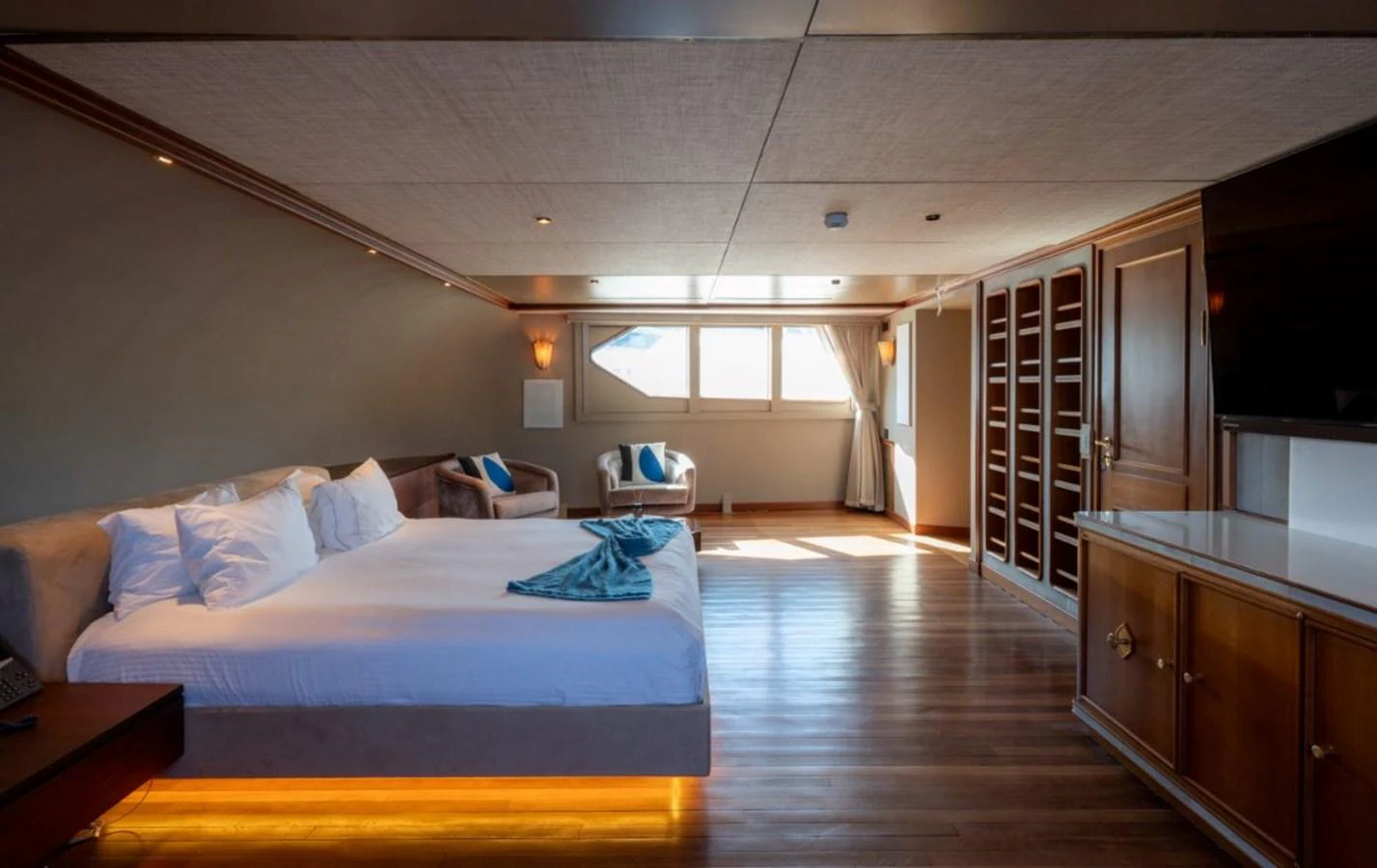 The master stateroom features a spacious layout with a large bed, seating area, and ample natural light. aboard STELLA FIERA II Yacht for Sale