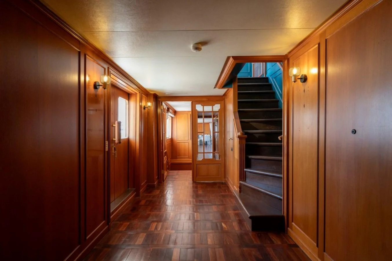 A warm, wood-paneled hallway with stairs leading to another level. aboard STELLA FIERA II Yacht for Sale