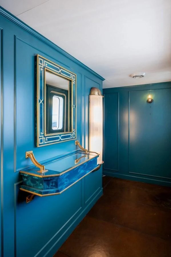 A stylish interior hallway featuring a unique blue wall-mounted console and a mirror. aboard STELLA FIERA II Yacht for Sale