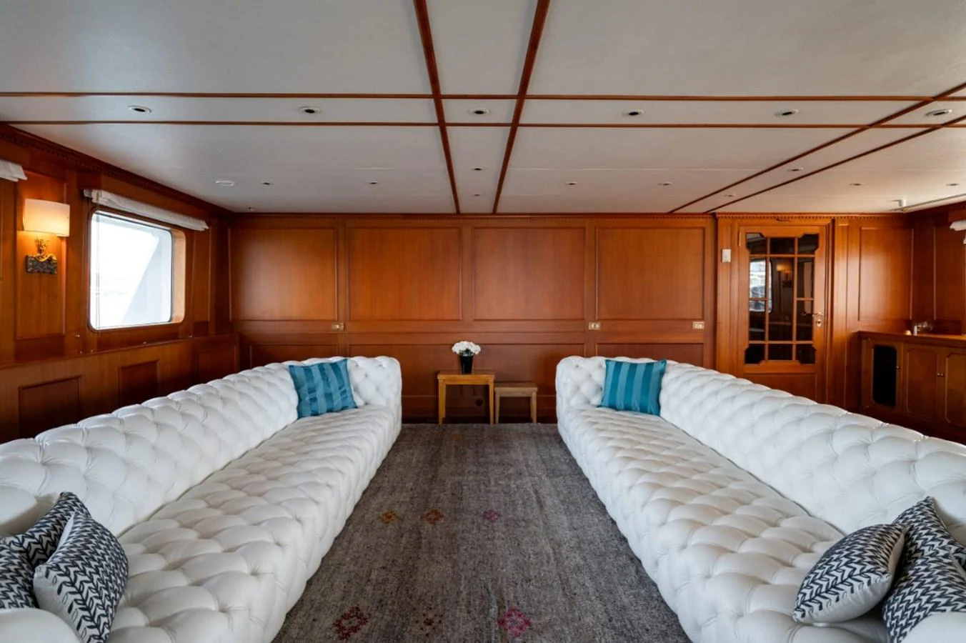 The salon features luxurious white tufted sofas and elegant wooden paneling, creating a sophisticated and inviting atmosphere. aboard STELLA FIERA II Yacht for Sale
