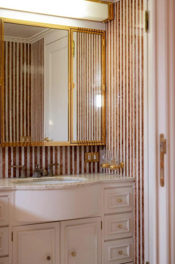 The bathroom features elegant striped walls and a marble countertop with gold accents. aboard STELLA FIERA II Yacht for Sale