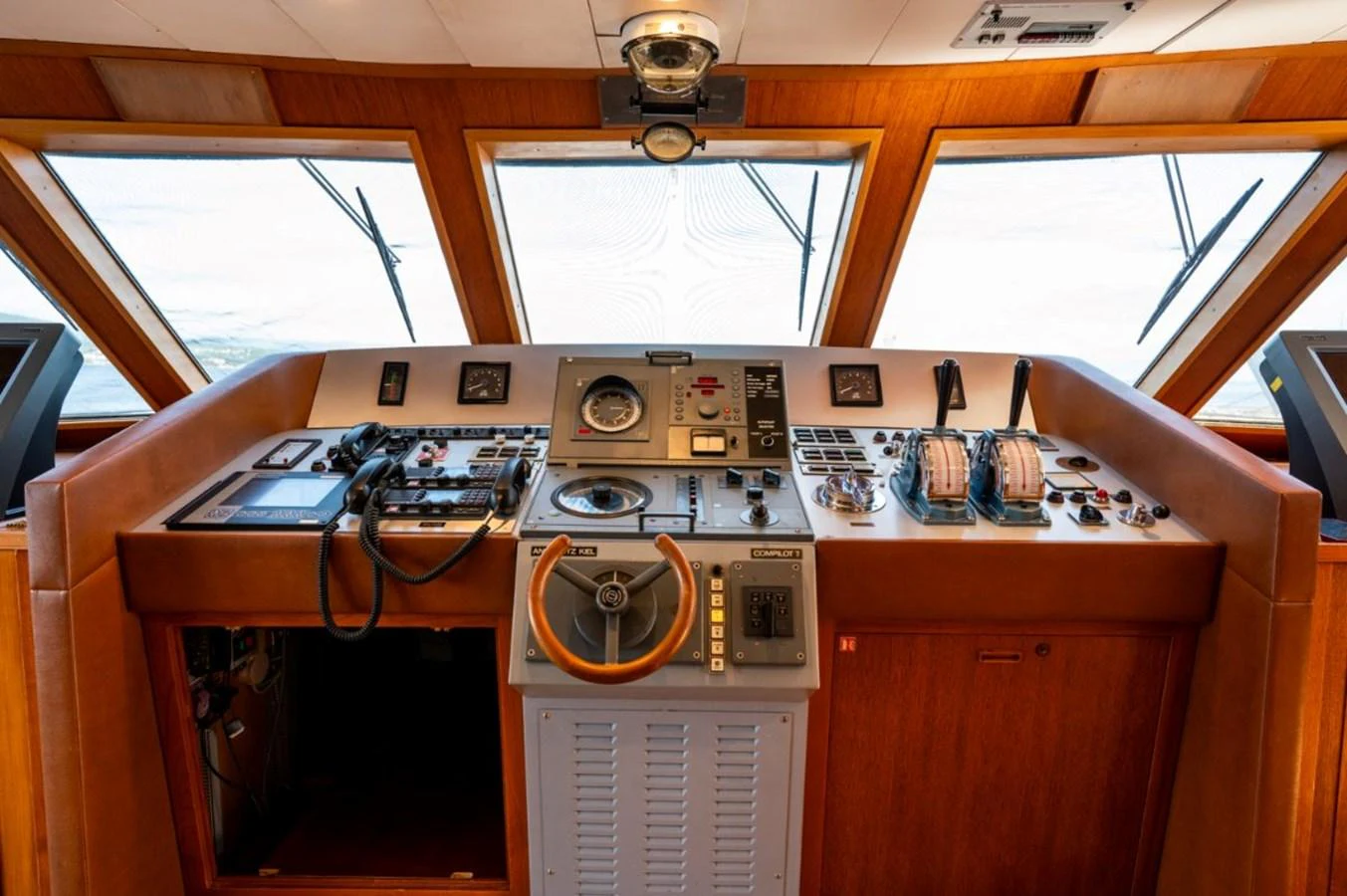 The helm station features a comprehensive array of navigation and control instruments set against a warm wood finish. aboard STELLA FIERA II Yacht for Sale