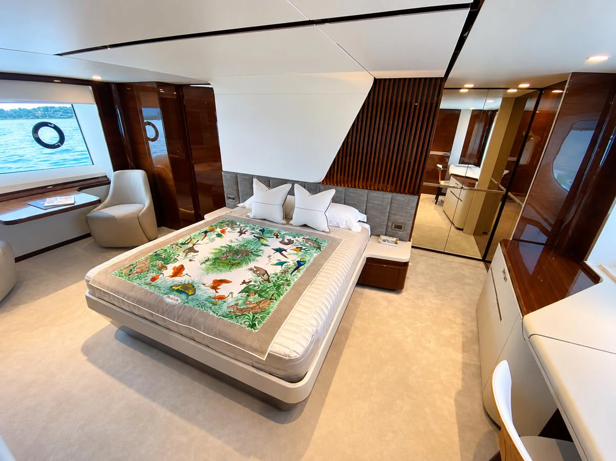 The master stateroom features a luxurious bed with a colorful quilt, surrounded by elegant wood paneling and large windows offering scenic views. aboard MOONFLOWER Yacht for Sale