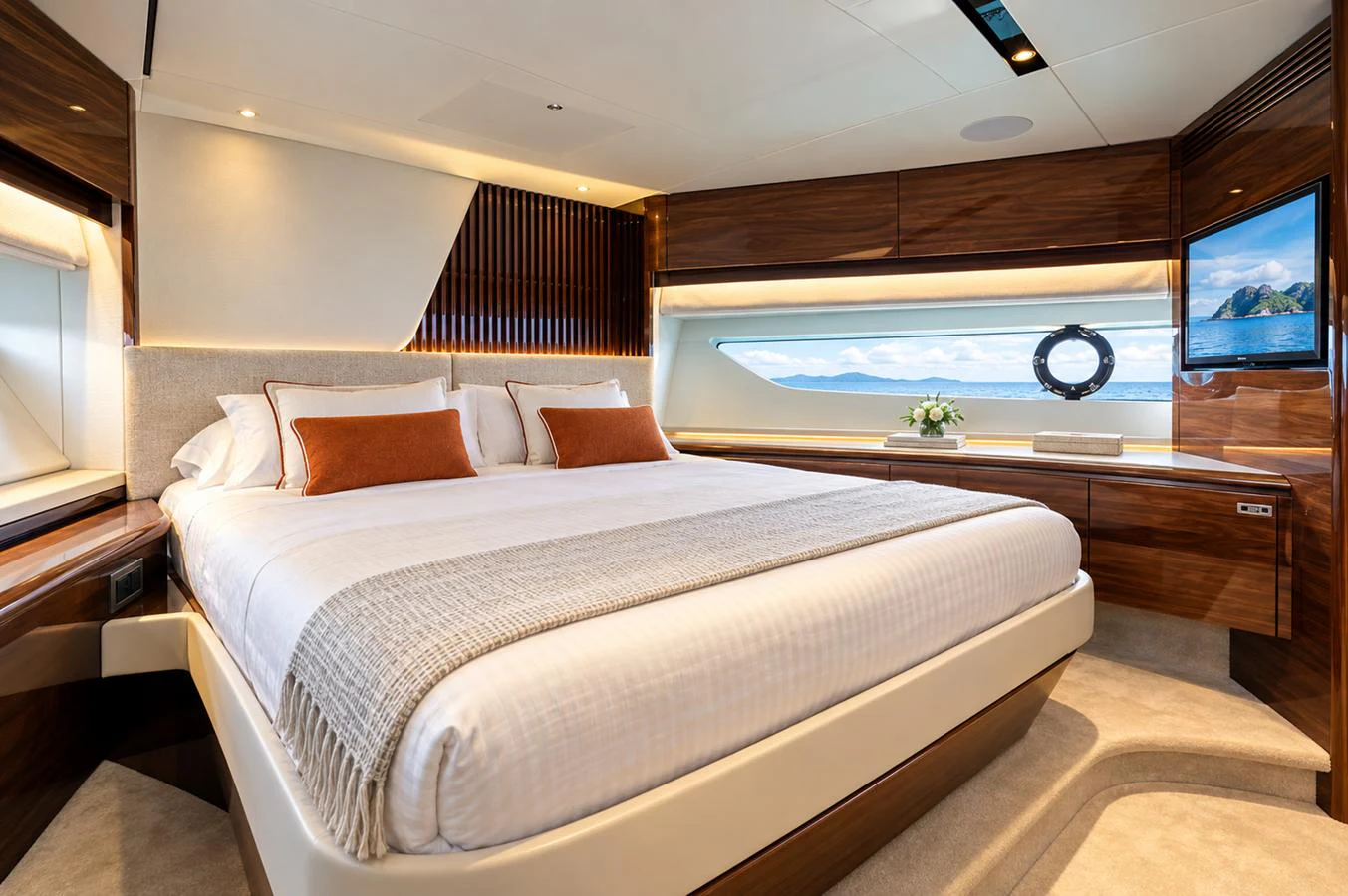 The master stateroom features a luxurious bed with elegant wood finishes and a scenic window view. aboard MOONFLOWER Yacht for Sale