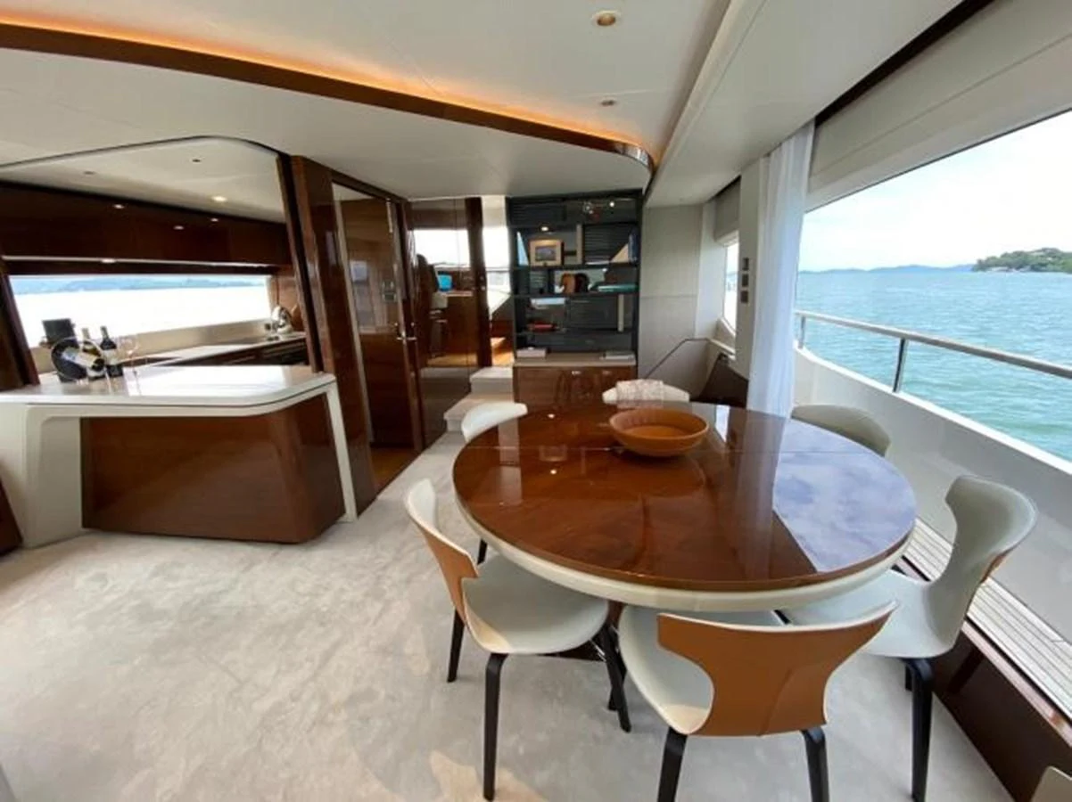 The yacht's dining area features a sleek, modern design with a round table and comfortable seating, complemented by large windows offering stunning sea views. aboard MOONFLOWER Yacht for Sale
