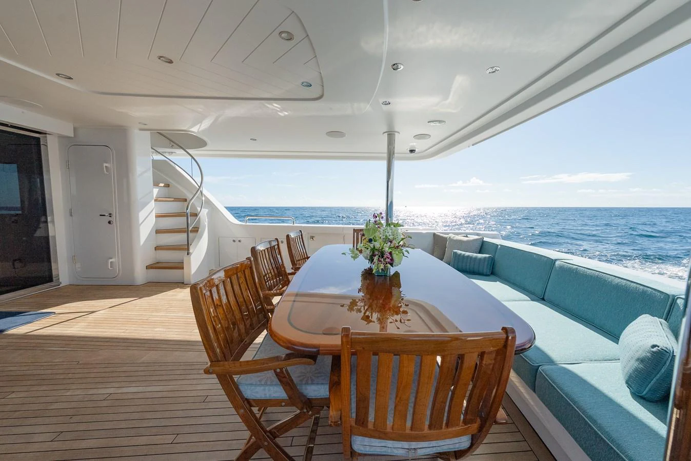 The aft deck features a spacious dining area with a wooden table and comfortable seating, offering stunning ocean views. aboard DETERMINATION Yacht for Sale