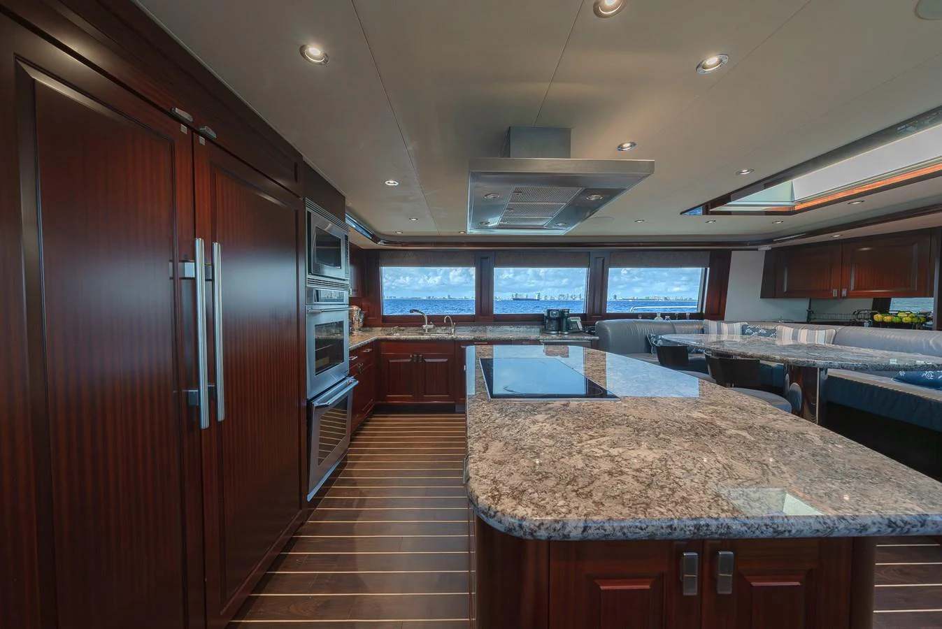 The galley features elegant wood cabinetry and modern appliances with a stunning ocean view through large windows. aboard DETERMINATION Yacht for Sale