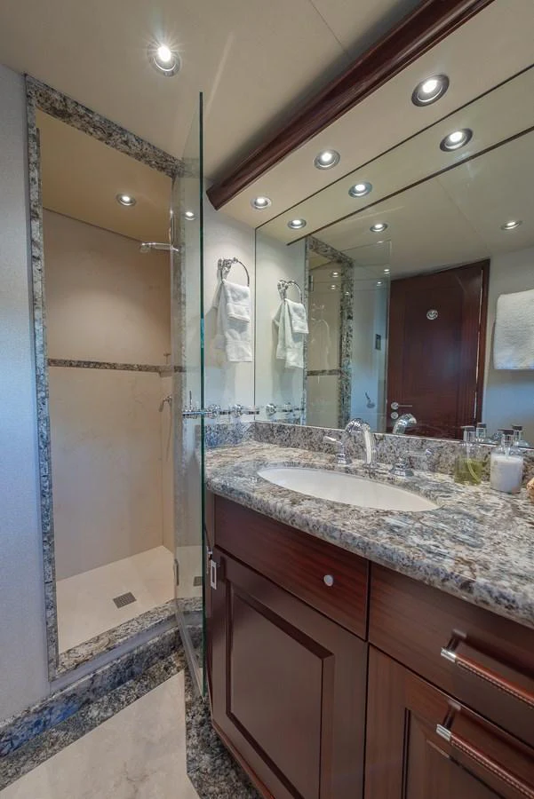 The yacht's bathroom features a sleek design with a glass-enclosed shower and elegant marble countertops. aboard DETERMINATION Yacht for Sale