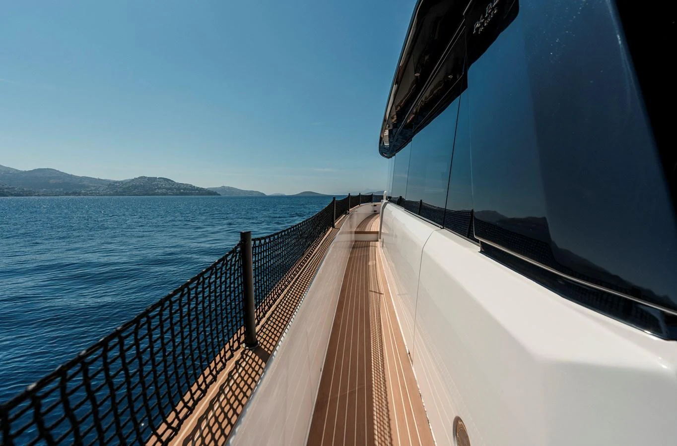 The sleek side deck of the yacht offers a stunning view of the open sea and distant coastline. aboard LUCKY LUKA Yacht for Sale
