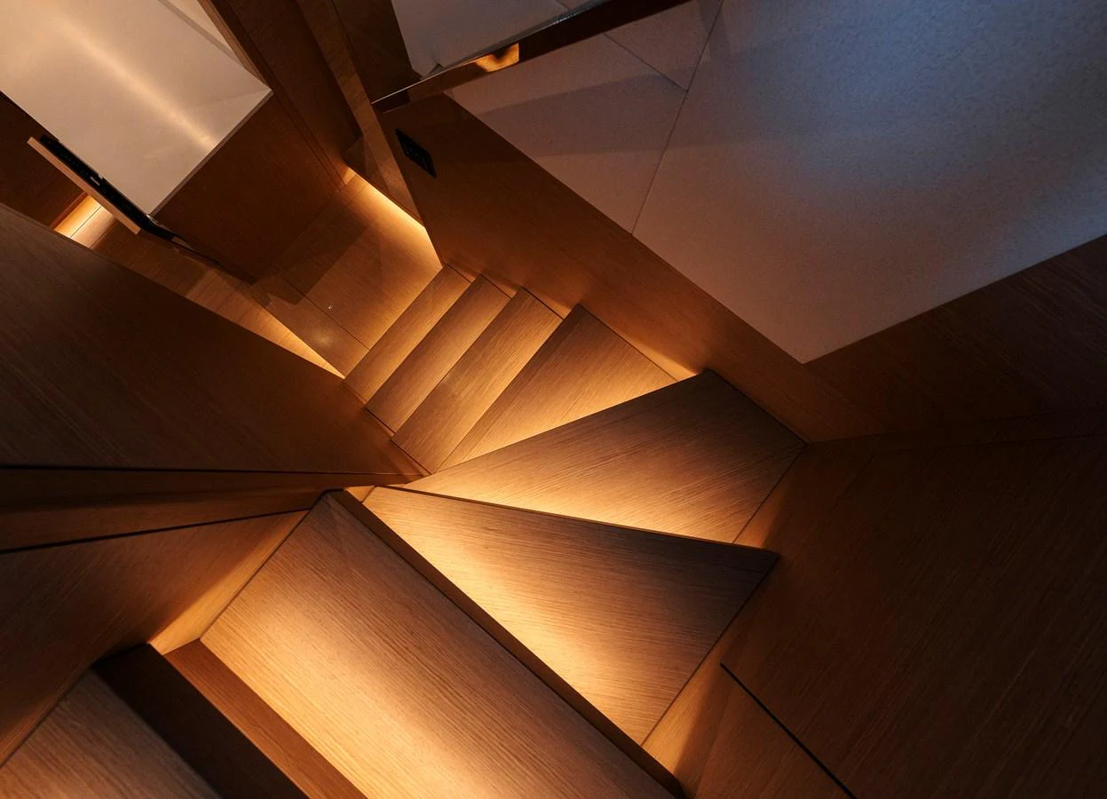 A modern, well-lit staircase with sleek wooden steps and ambient lighting. aboard LUCKY LUKA Yacht for Sale