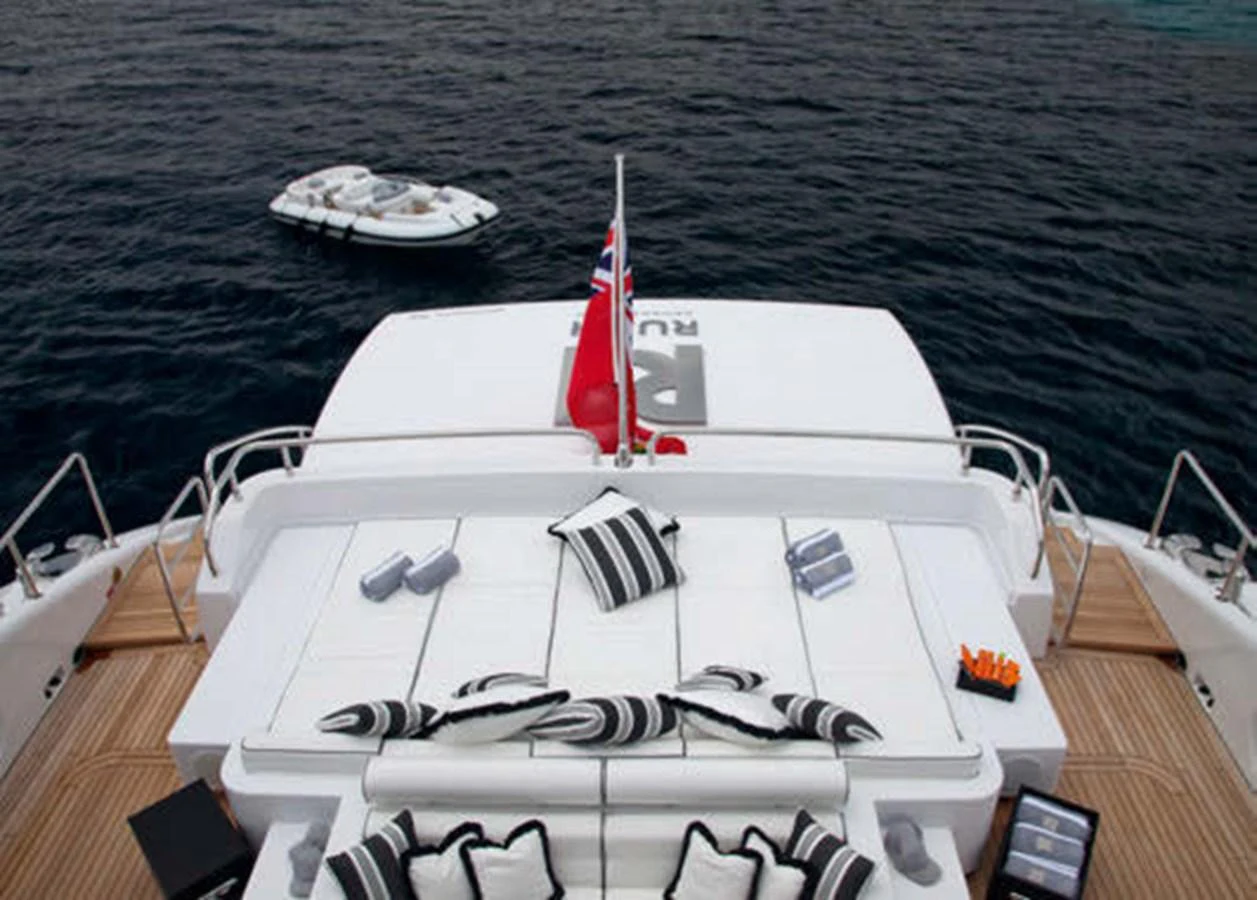 The aft deck features a luxurious sunbathing area with plush cushions and a stunning view of the water. aboard RUSH Yacht for Sale