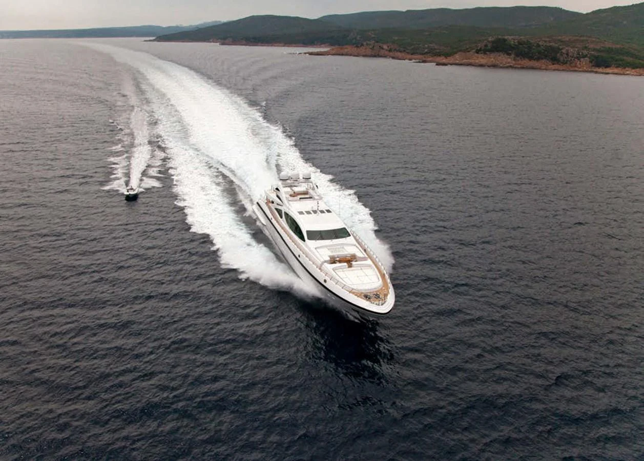 A sleek yacht cruises swiftly through open waters, leaving a trail of white wake behind. aboard RUSH Yacht for Sale