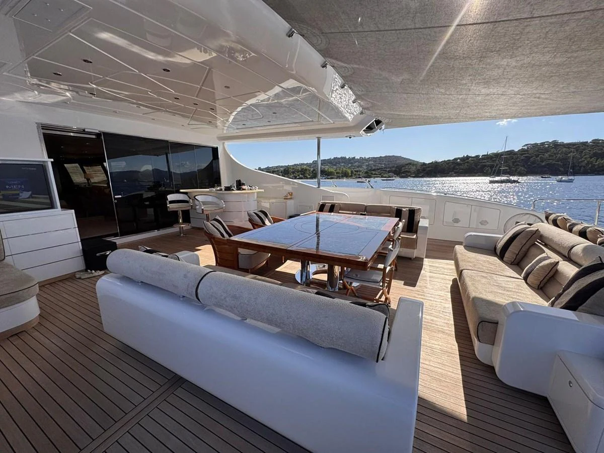The aft deck features a spacious seating area with a dining table, perfect for enjoying meals with a view of the water. aboard RUSH Yacht for Sale