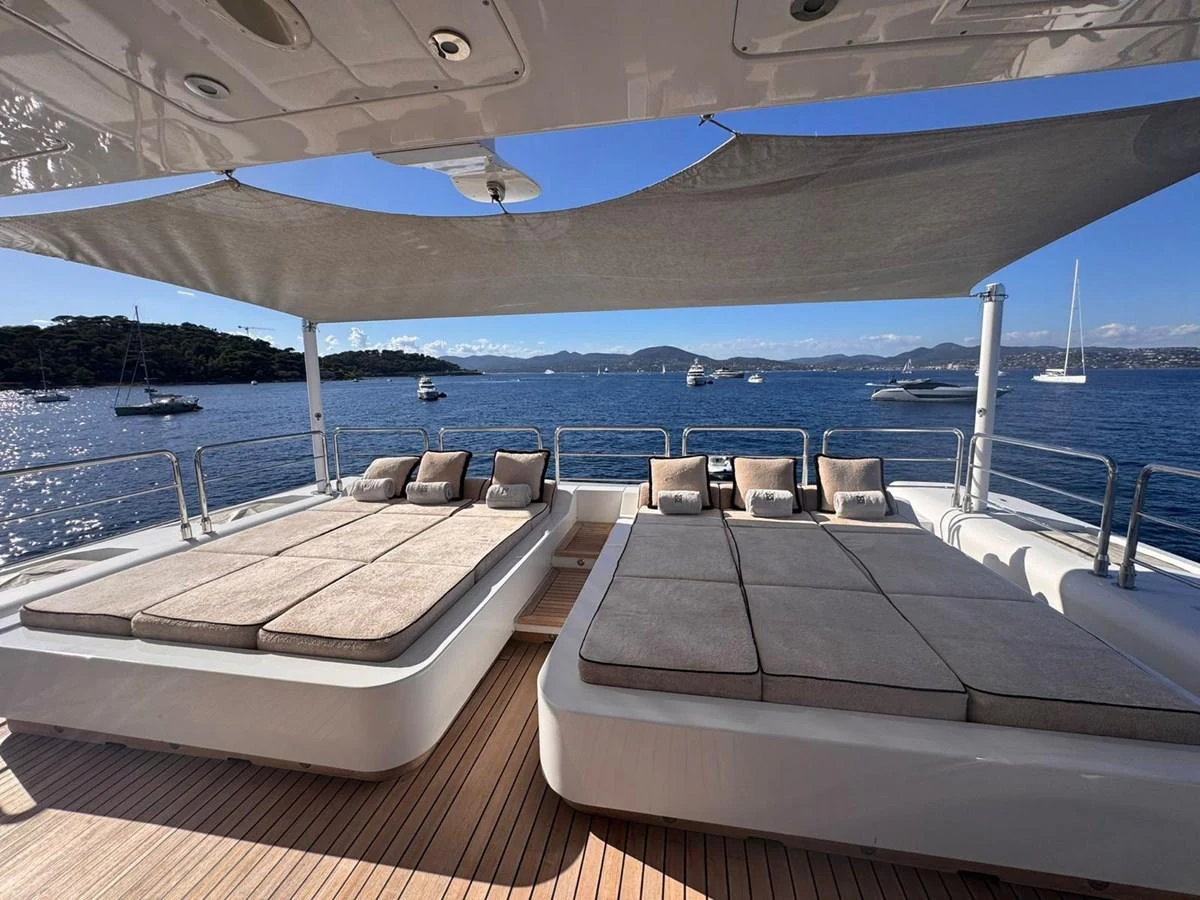 The yacht's sundeck features luxurious sun loungers under a stylish shade, offering stunning views of the surrounding waters. aboard RUSH Yacht for Sale