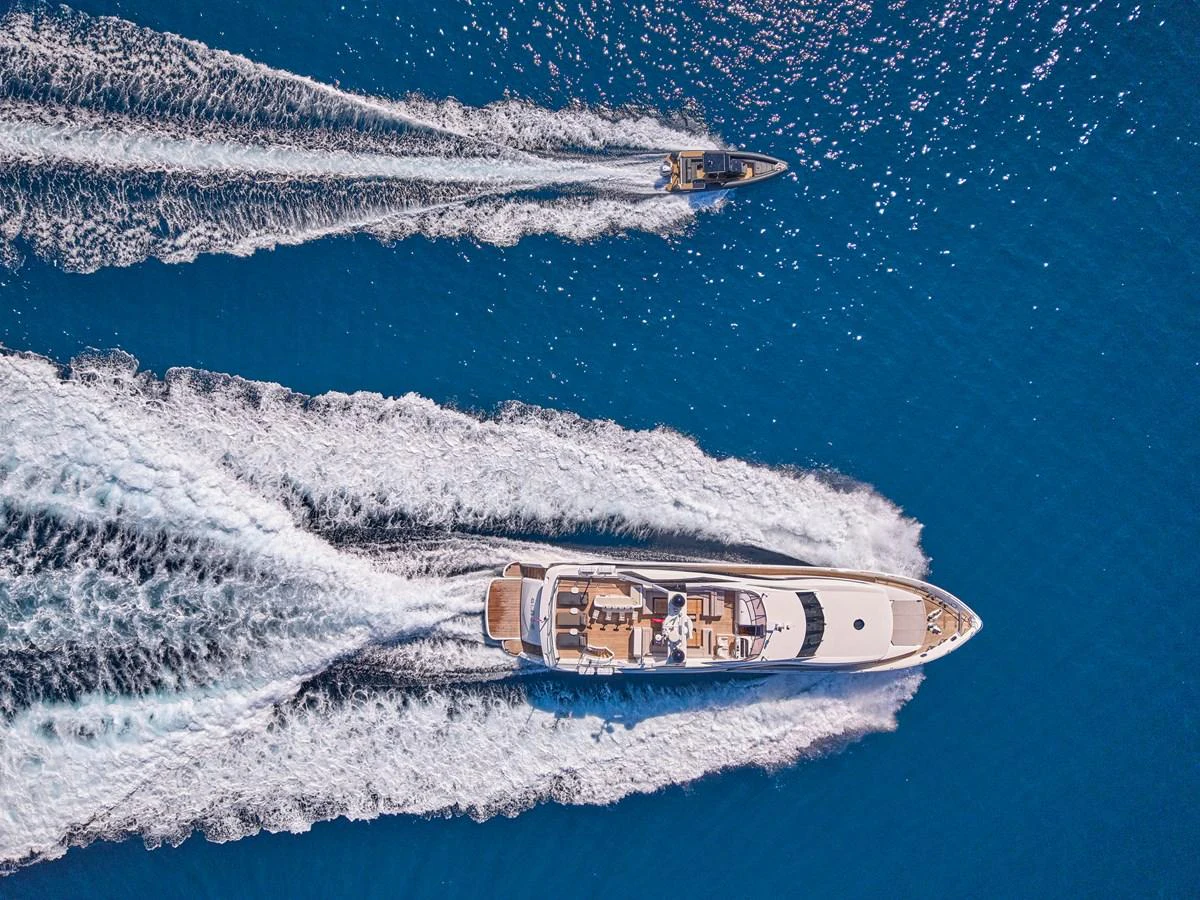 A stunning aerial view of a luxurious yacht cruising through the open sea, accompanied by a smaller vessel. aboard BLADE I Yacht for Sale
