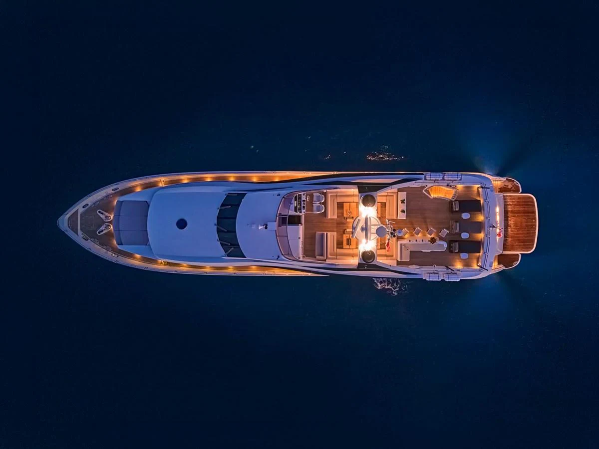 An aerial view of a yacht illuminated beautifully against the dark water at night. aboard BLADE I Yacht for Sale