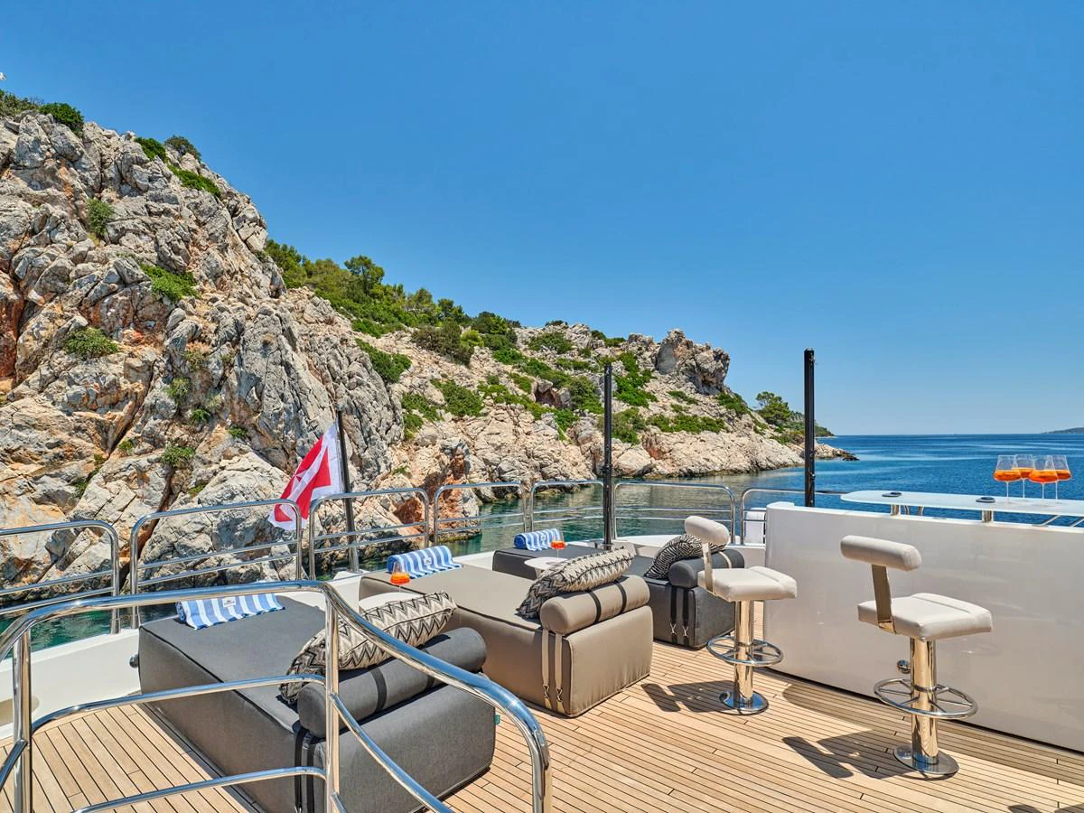 The aft deck offers a luxurious lounging area with plush seating and stunning views of the rocky coastline. aboard BLADE I Yacht for Sale