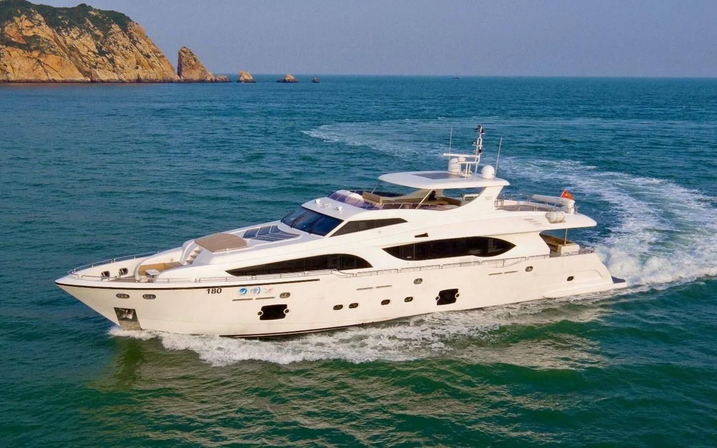 A luxurious yacht cruises through serene blue waters with a scenic coastline in the background. aboard HEYSEA ASTERIA 126/1 Yacht for Sale
