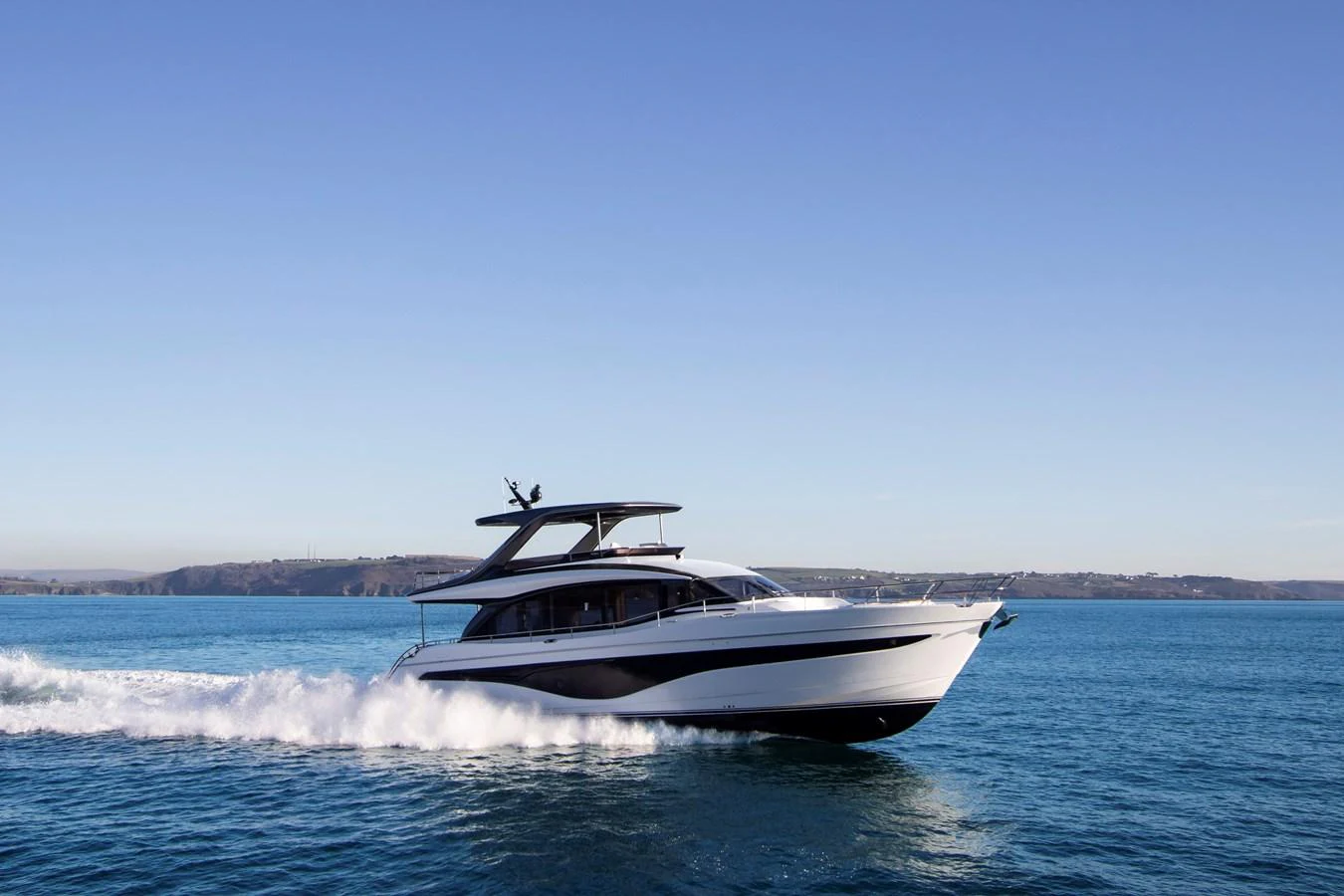 A sleek yacht cruises swiftly across the open water under a clear blue sky. aboard PRINCESS Y72 Yacht for Sale