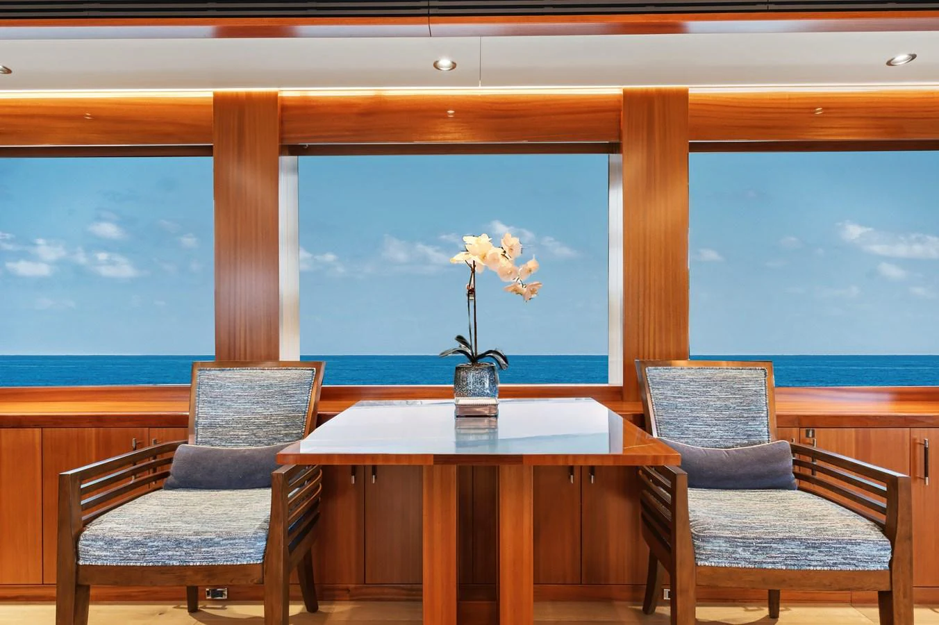 The yacht's interior features a serene seating area with ocean views through large windows. aboard SEAS THE DAY Yacht for Sale