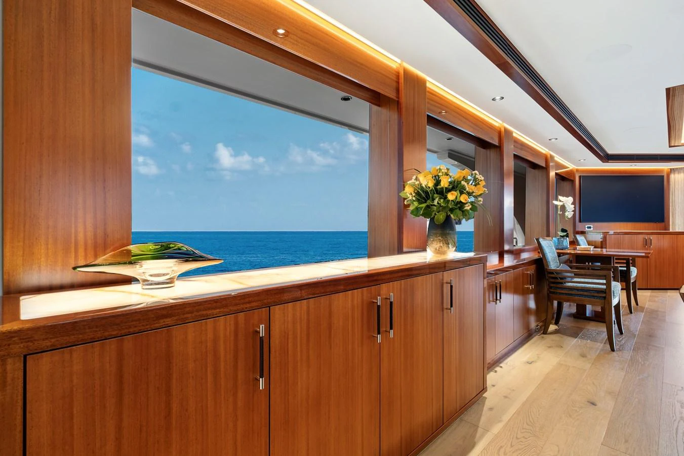 The yacht's interior features elegant wooden cabinetry and large windows offering stunning ocean views. aboard SEAS THE DAY Yacht for Sale
