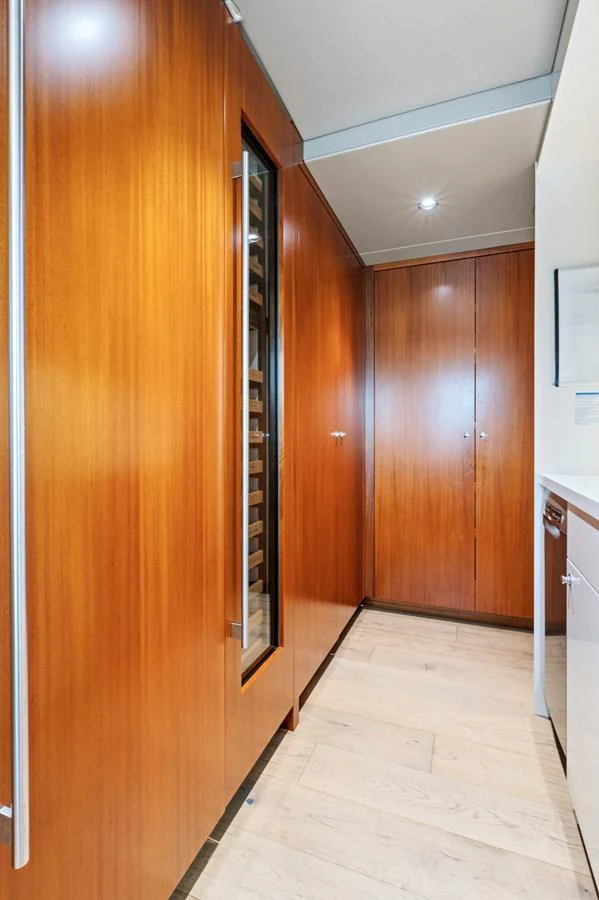 The image showcases a sleek hallway with wooden paneling and modern cabinetry. aboard SEAS THE DAY Yacht for Sale