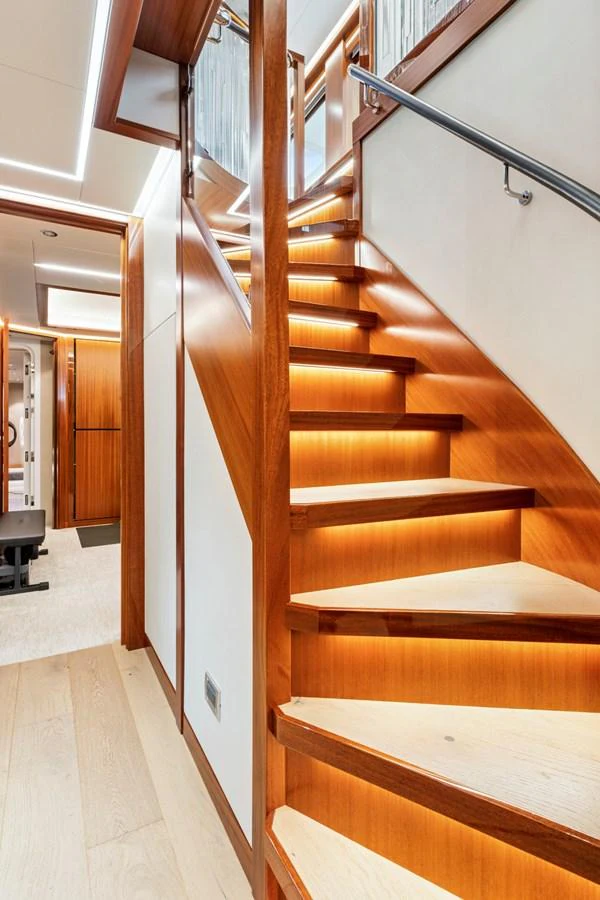 A beautifully crafted wooden staircase with ambient lighting leads to the upper deck. aboard SEAS THE DAY Yacht for Sale