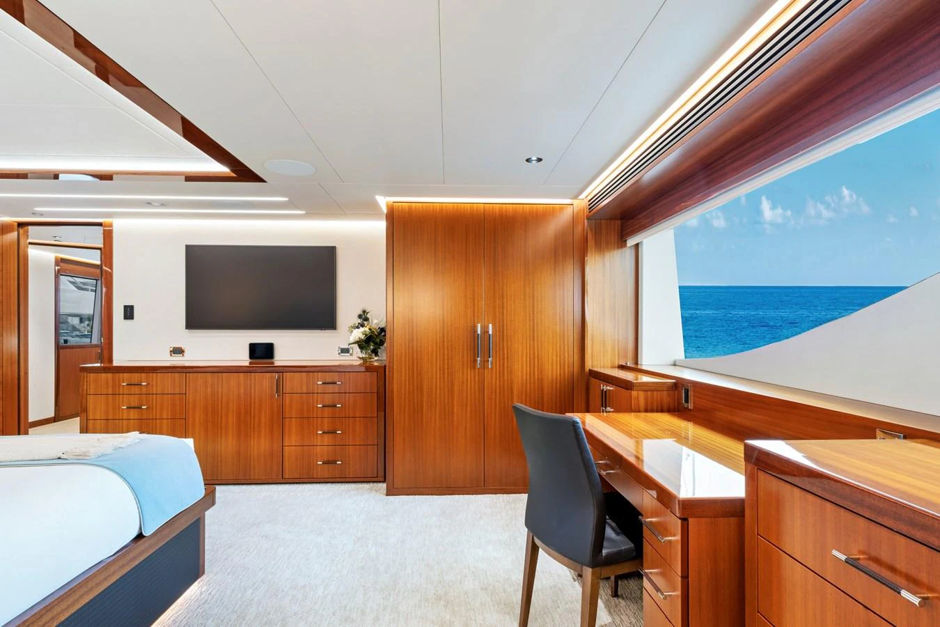 The stateroom features elegant wood finishes, a large window with an ocean view, and modern furnishings. aboard SEAS THE DAY Yacht for Sale