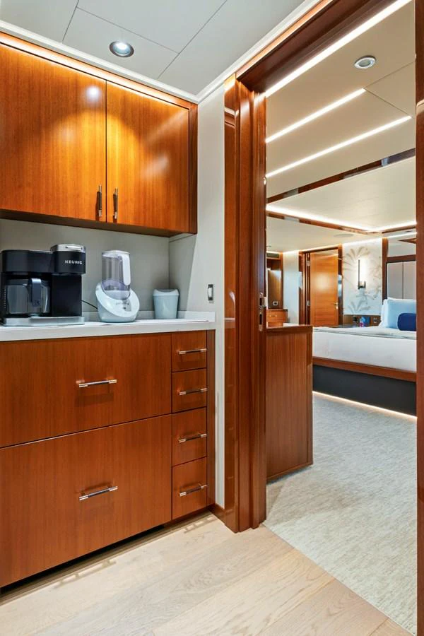 The yacht's galley features warm wood cabinetry and modern appliances, leading into a cozy stateroom. aboard SEAS THE DAY Yacht for Sale