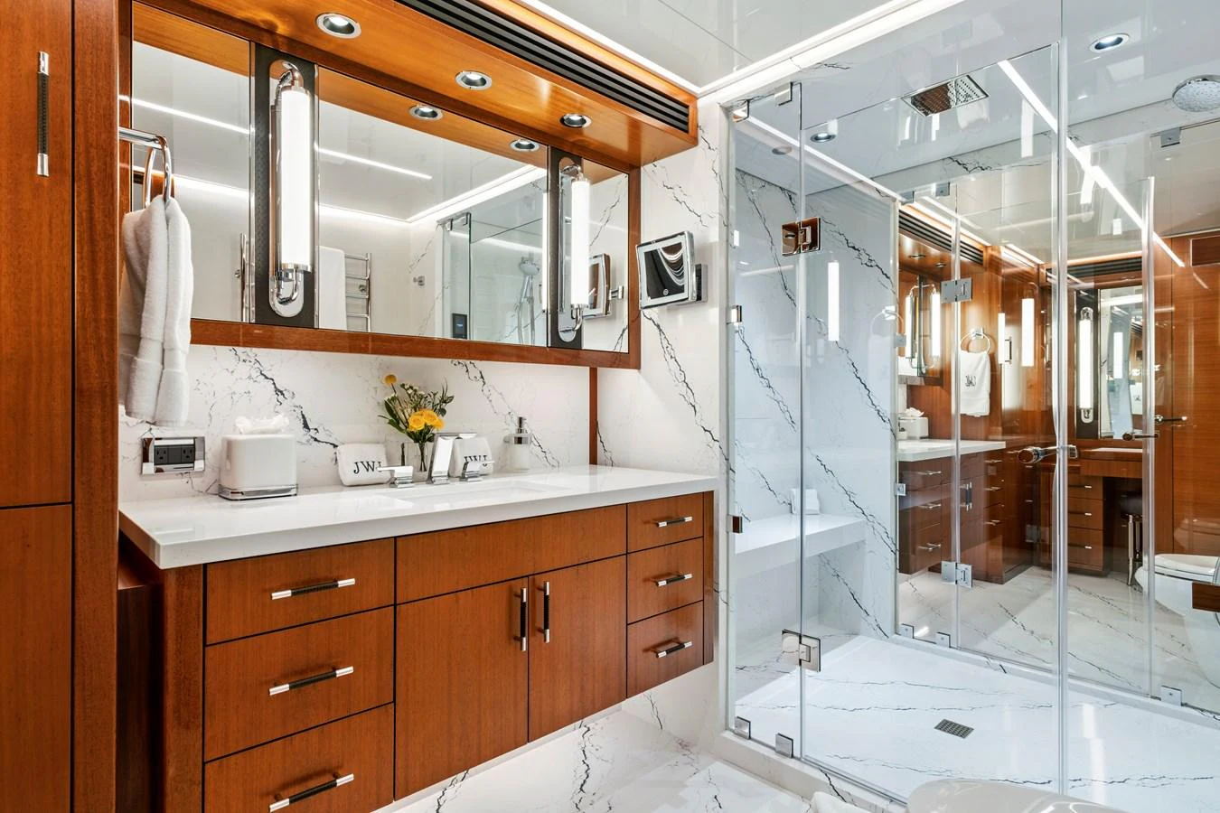 The yacht's bathroom features elegant wood cabinetry, a spacious glass-enclosed shower, and luxurious marble accents. aboard SEAS THE DAY Yacht for Sale
