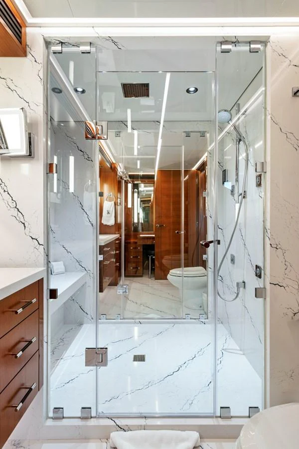The yacht's bathroom features a luxurious glass-enclosed shower with elegant marble accents. aboard SEAS THE DAY Yacht for Sale
