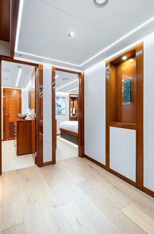 The yacht's interior features a modern hallway with sleek wooden finishes and ambient lighting. aboard SEAS THE DAY Yacht for Sale