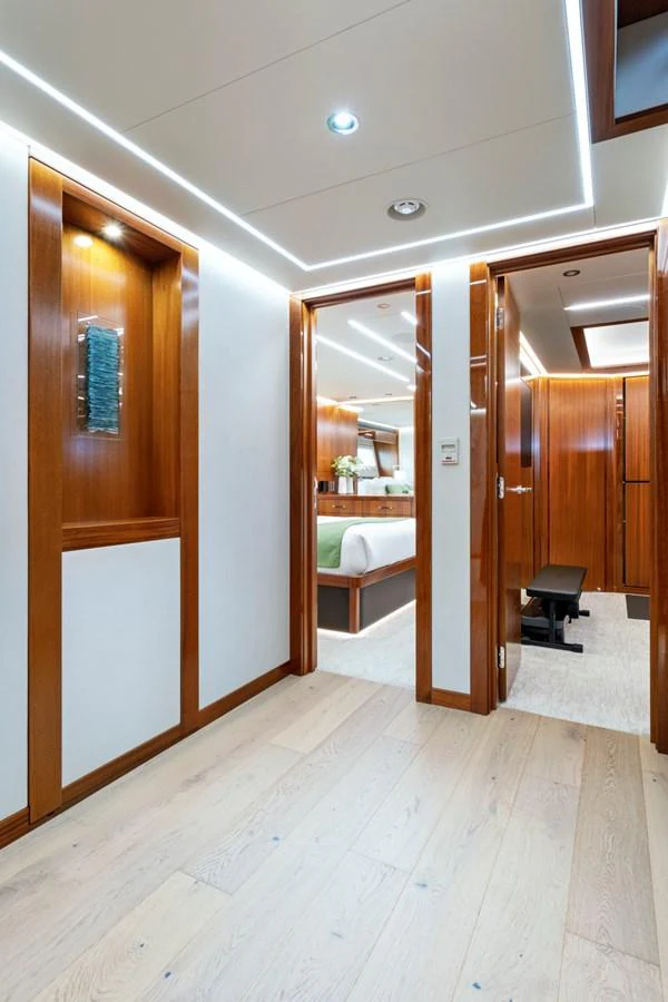 The yacht's interior features a hallway leading to a bedroom and another room, showcasing elegant wood finishes and modern lighting. aboard SEAS THE DAY Yacht for Sale