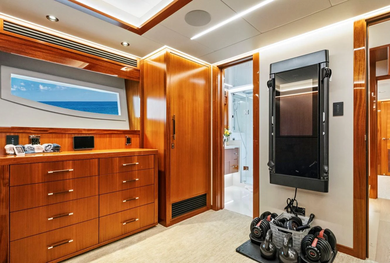 The yacht's interior features a sleek wooden finish with modern amenities and a fitness area. aboard SEAS THE DAY Yacht for Sale