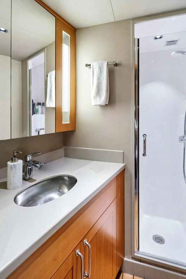 A modern yacht bathroom featuring a sleek sink and a glass-enclosed shower. aboard SEAS THE DAY Yacht for Sale