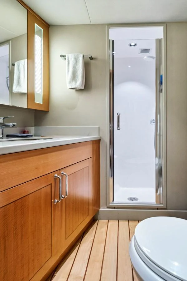 The yacht's bathroom features a sleek shower, wooden cabinetry, and modern fixtures. aboard SEAS THE DAY Yacht for Sale