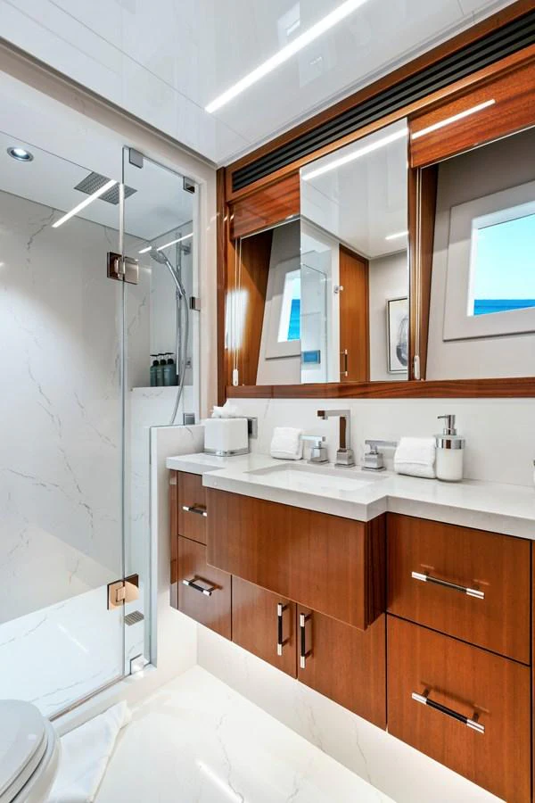 The yacht's bathroom features sleek wooden cabinetry and a modern glass-enclosed shower. aboard SEAS THE DAY Yacht for Sale