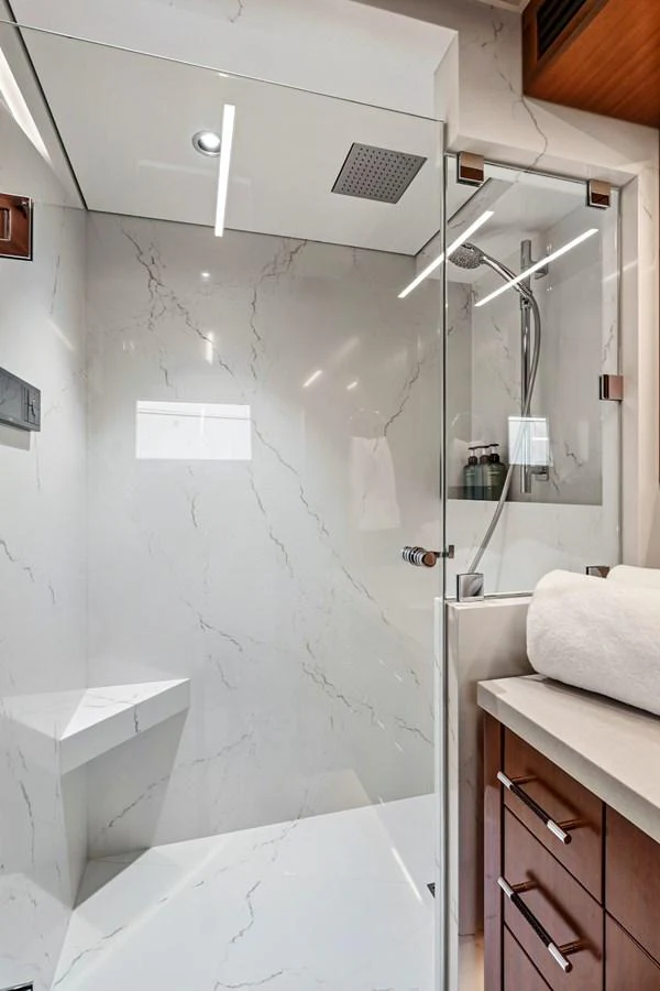 The yacht's bathroom features a modern glass-enclosed shower with elegant marble walls. aboard SEAS THE DAY Yacht for Sale
