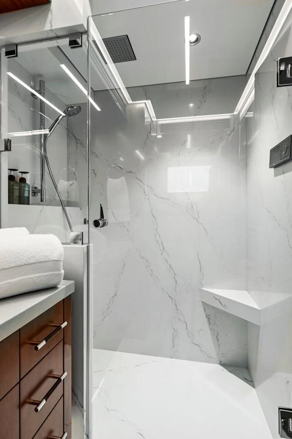 The yacht's bathroom features a sleek, modern design with marble walls and a glass-enclosed shower. aboard SEAS THE DAY Yacht for Sale