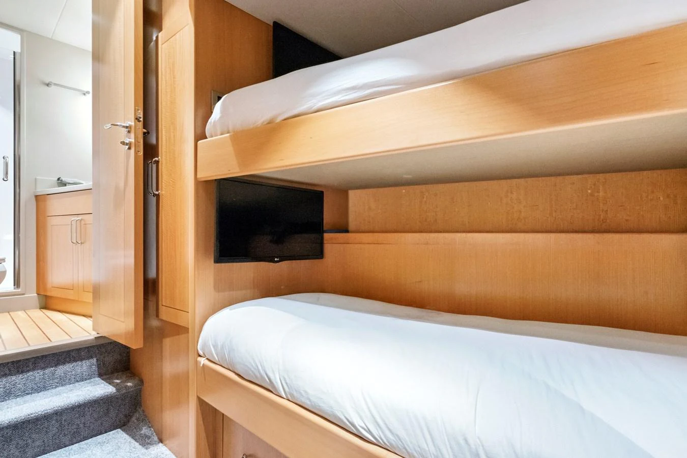 The cozy bunk cabin features two neatly arranged beds with a small television for entertainment. aboard SEAS THE DAY Yacht for Sale