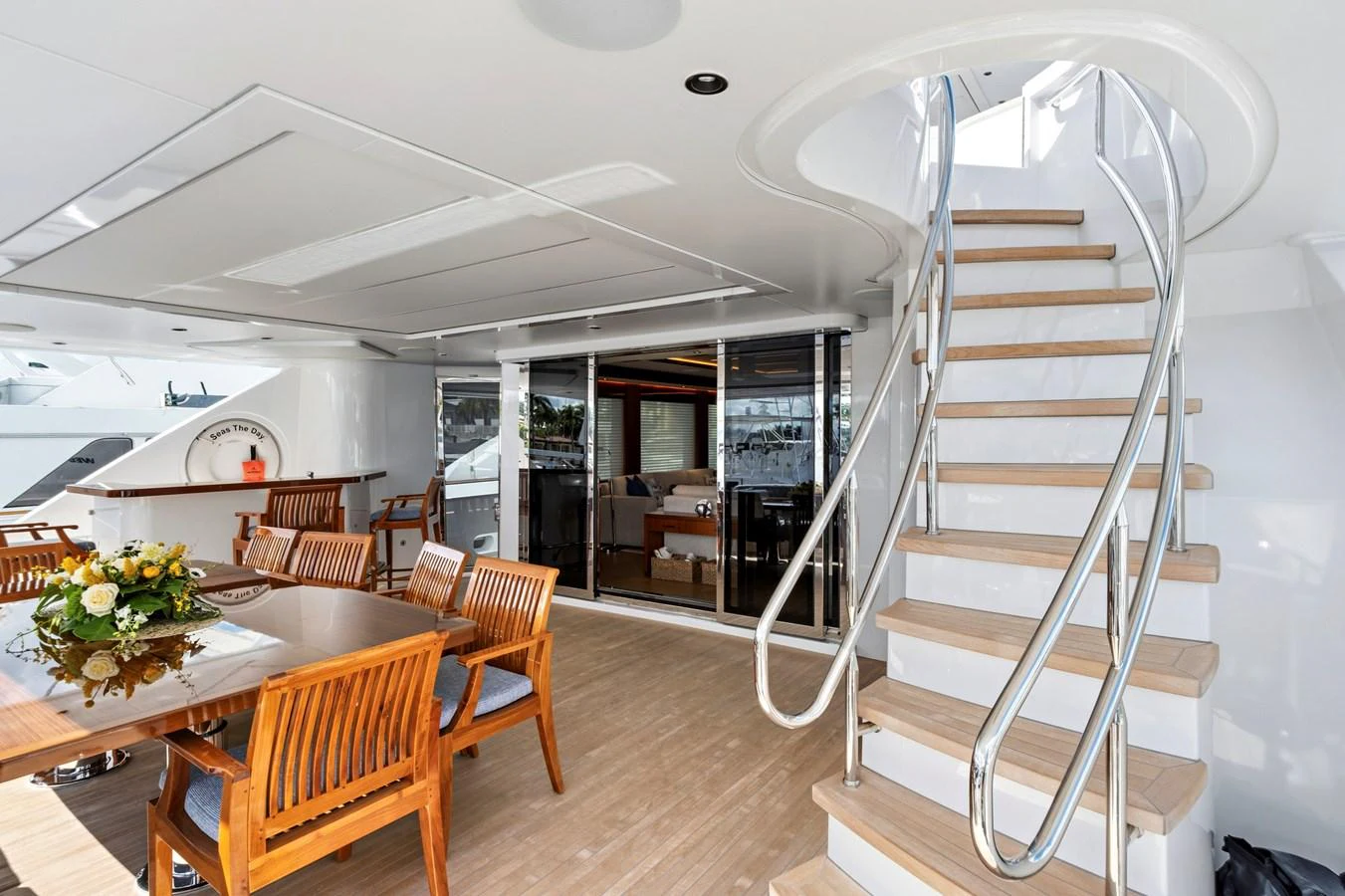 The aft deck features elegant wooden furniture and a stylish staircase leading to the upper deck. aboard SEAS THE DAY Yacht for Sale