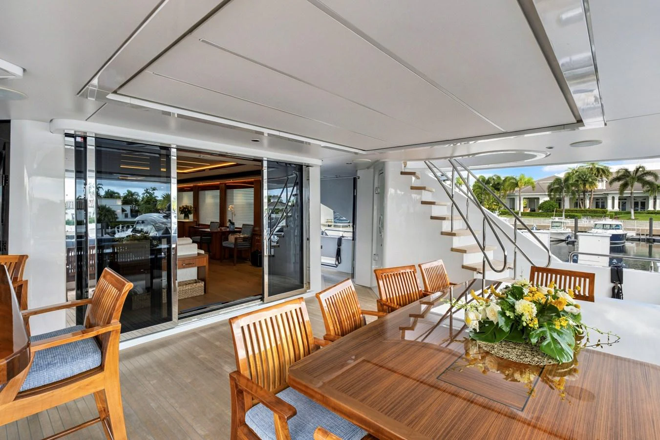 The aft deck features a spacious dining area with elegant wooden furniture and a view of the marina. aboard SEAS THE DAY Yacht for Sale