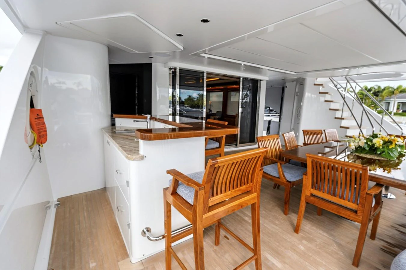 The aft deck features a stylish dining area with wooden chairs and a bar counter, perfect for alfresco meals. aboard SEAS THE DAY Yacht for Sale