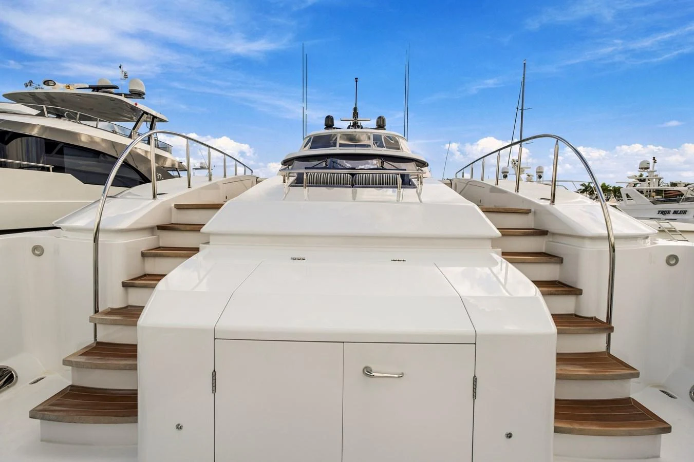 The yacht's aft deck features elegant steps leading up to the upper deck under a clear blue sky. aboard SEAS THE DAY Yacht for Sale