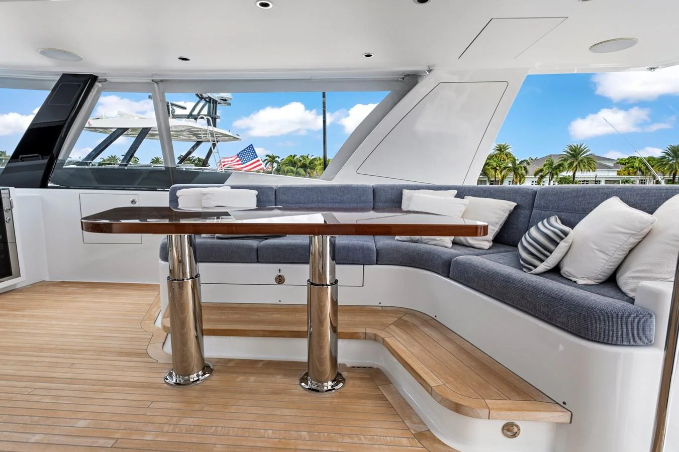 The aft deck features a comfortable seating area with a polished wooden table, perfect for outdoor dining and relaxation. aboard SEAS THE DAY Yacht for Sale