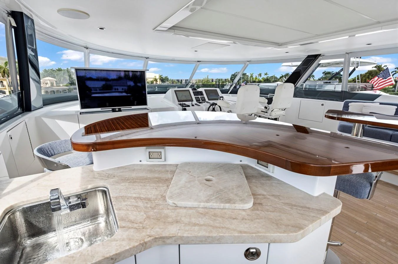 The helm station features modern navigation equipment and a stylish bar area with a sink. aboard SEAS THE DAY Yacht for Sale