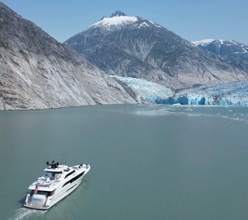A sleek yacht cruises through serene waters with a stunning mountainous backdrop. aboard SEAS THE DAY Yacht for Sale